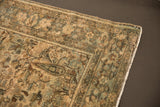 Worn floral bouquet on distressed Hamadan rug corner in muted ivory, pale teal, and gold.