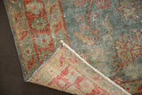 Distressed Hamadan rug corner, with worn aqua and terra cotta pile revealing woven foundation.