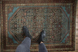 An overhead view showing the mostly even wear and Herati pattern on a distressed vintage Malayer rug.