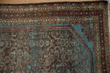 Detail of the brilliant blue corner spandrel and distressed low pile on a vintage Persian rug.