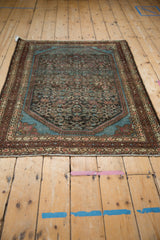 Angled profile of a vintage Malayer rug showing its distressed Herati pattern and rich blue spandrels.