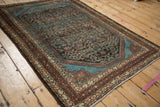 Angled view of a distressed Malayer rug highlighting the texture and brilliant blue corner spandrels.