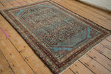 Full perspective view of a distressed Malayer rug, showing its Herati pattern and bright blue corner spandrels.