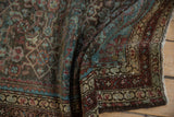 Draped corner of a vintage Malayer rug showing the time-softened pile and madder red border.