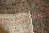 Distressed Sarouk rug corner revealing worn red, ocean blue-green pile and tightly woven foundation.