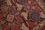 Detail of antique Afshar rug's allover geometric design in navy, madder red, and ivory, with wear.