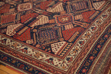 Intricate geometric borders and field patterns in navy, red, and ivory on the antique Afshar rug.