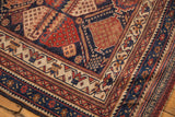 Corner of an antique Afshar rug displaying intricate geometric patterns in navy, madder red, and ivory.