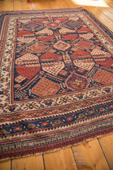 Secured end of antique Afshar rug; geometric patterns in navy, red, and ivory.