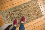 Vintage distressed Sarouk runner showcasing allover floral sprays in antique ivory, blue-green, and chocolate brown.
