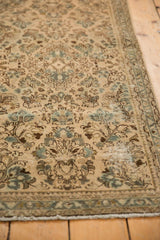 Vintage distressed Sarouk runner showcasing ivory and blue floral sprays, textured wear.