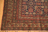 Corner of an antique Persian Malayer rug, intricate Herati, madder red, navy, dusty gold borders, and fringe.