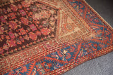 Antique Kula rug corner showing sapphire blue vine border and low pile floral field.