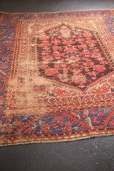 Antique Kula rug's sapphire blue meandering vine border and worn field, revealing foundation.