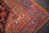 Detail of antique Kula rug's sapphire blue border, red meandering vines, and worn pile texture.