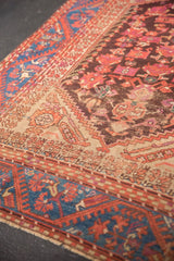 Antique Kula rug's sapphire blue meandering vine border and worn aubergine floral field.
