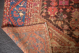 Antique Kula rug folded back, revealing its woven reverse and visibly worn sapphire blue pile.