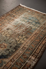 Distressed Hamadan rug showcasing faded geometric motifs in dusty teal and sand.