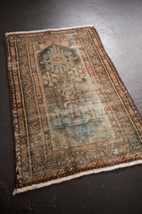 Distressed vintage Hamadan rug corner, revealing worn pile, exposed foundation, and short fringe.