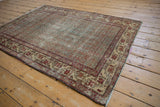 Distressed vintage Hamadan rug corner, with faded blue Boteh pattern and red border.