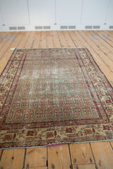 Distressed vintage Hamadan rug's fringed end, with worn madder red and faded ocean green.