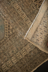 Distressed vintage Jaldar rug with worn pile, geometric patterns, and folded edge revealing reverse.