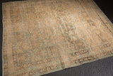 Faded sand, blue, brown floral motifs on a vintage Northwest Persian rug's worn pile.
