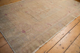 Distressed Oushak rug with worn pile, foundation visible, subtle pictorial design in beige and blush.