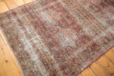 Vintage Persian Meshed rug detail: worn cochineal red milfleur field, starburst medallions, foundation visible.
