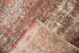 Folded vintage Meshed rug corner, revealing worn cochineal red, ivory pile and exposed foundation.