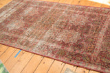 Persian Meshed rug's worn corner reveals cochineal red milfleur patterns and exposed foundation.