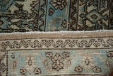 Distressed vintage rug pile shows faint foundation, faded blue motifs, and hand-knotted reverse.