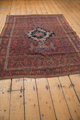 Vintage Bijar rug's secured end, revealing worn fringe and madder red, navy blue Herati patterns.