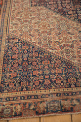 Antique Persian Senneh rug with intricate navy, madder red, ivory Herati pattern, showing wear.