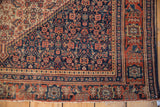 Antique Senneh rug's corner showcasing Herati pattern, madder red border, and wear revealing foundation.
