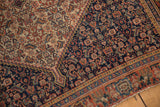 Antique Senneh rug's intricate Herati design transitioning across ivory and navy fields.
