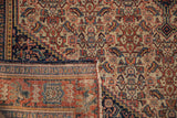 Folded antique Senneh rug detail showing intricate Herati pattern, even pile wear, and woven foundation.