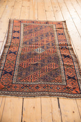 Antique Belouch rug corner detail: geometric lattice, madder red, navy blue, and soft pile.