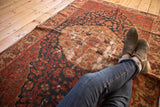 Antique Malayer rug close-up: brick red, navy floral roundel medallion with prominent foundation wear.