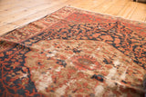 Antique Malayer rug corner: brick red floral patterns, navy accents, beige field, with visible foundation.