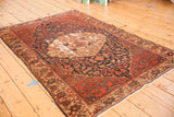 Intricate floral cross sections in navy and brick red, showing foundation wear on antique Malayer rug.