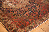 Antique Malayer rug corner showing brick red and navy floral patterns, with foundation clearly visible.