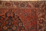 Corner of antique Malayer rug, brick red field, navy floral pattern, visible foundation wear.