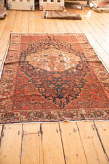 Antique Malayer rug's secured end, featuring a brick red floral border and short fringe.
