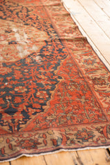 Antique Malayer rug's brick red field, featuring navy floral patterns and visible foundation wear.