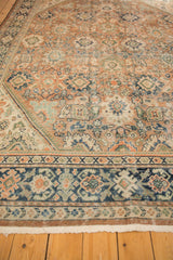 Close-up of distressed vintage Mahal carpet: worn terracotta, navy blue border, and sage green palmette motifs.