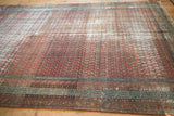 The storied texture and time-softened terracotta and blue tones of a distressed Persian runner.