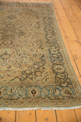 Distressed Kashan rug end with fringe, showing worn ivory and blue floral border.