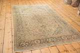 Vintage distressed Kashan rug with faded ivory and blue floral patterns, showing even wear.