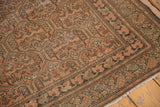 Distressed vintage Malayer rug corner showing rust, brown boteh patterns, and fringe.